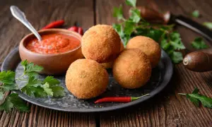 Arancini dorés et croustillants, accompagnés de sauce tomate et de piment. Une recette parfaite pour un apéritif gourmand.