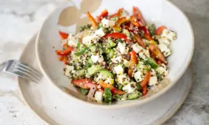 Salade quinoa colorée avec des dés de feta, concombre, poivrons rouges et herbes fraîches. Un plat sain et savoureux.