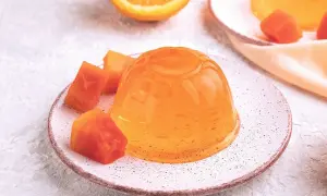 Une gelée orange brillante, servie avec des morceaux de fruits, parfaite pour apprendre comment faire de la gelée maison.