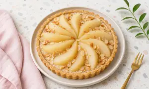 Tarte amandine aux poires, joliment décorée de lamelles d'amandes grillées. Un délice gourmand prêt à être dégusté.