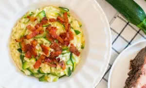 Risotto crémeux aux courgettes, garni de croustillantes tranches de guanciale. Un délice italien.