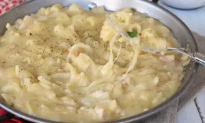 Un plat réconfortant de pasta e patate crémeux, garni de poivre noir fraîchement moulu. Une fourchette soulève une portion filante de ce délice.