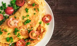 Une savoureuse omelette grecque, garnie de tomates cerises et de persil frais, sur une assiette blanche.