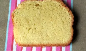 Une tranche de torta margherita, moelleuse et dorée, posée sur une serviette rayée rose et blanche.