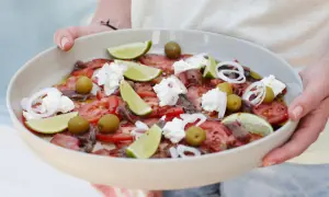 Salade colorée avec tomates, olives, anchois, oignons rouges, quartiers de citron vert et éclats de ricotta. Une idée recette ricotta fraîche et estivale.