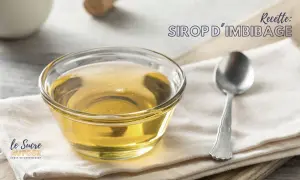 Un bol de sirop d'imbibage doré, parfait pour une génoise moelleuse. Une cuillère repose à côté.