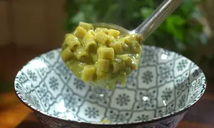Une louche de pâtes ditalini dans une sauce crémeuse aux petits pois, parfaite pour une recette italienne simple et savoureuse.