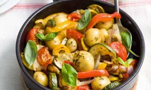 Poêlée de légumes colorés avec des pommes de terre grenaille, poivrons, courgettes et tomates, garnie de basilic frais.