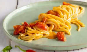 Un plat de scarpariello pasta, des spaghettis aux tomates cerises et au piment rouge, sur une assiette verte.