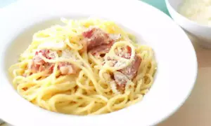 Un plat de pâtes à la carbonara crémeuses, garni de lardons croustillants et de parmesan râpé, prêt à être dégusté.
