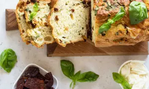 Un délicieux cake salé aux tomates séchées et basilic, parfait pour l'apéro. Des tranches sont coupées, révélant sa mie moelleuse.