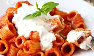 Pâtes rigatoni en sauce tomate, généreusement nappées de stracciatella crémeuse et garnies d'une feuille de basilic frais. Un délice !