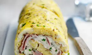 Une savoureuse omelette roulée au four, garnie de jambon et de fromage frais, parsemée de ciboulette. Un délice !