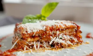 Tranche d'aubergine parmigiana, garnie de parmesan râpé et d'une feuille de basilic frais. Un délice italien.