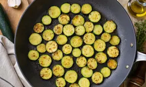 Rondes tranches de courgette au four, dorées et légèrement grillées dans une poêle, prêtes à être dégustées.