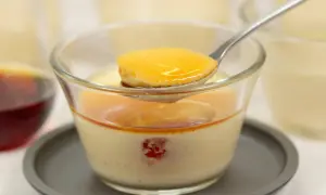 Cuillère de crème caramel onctueuse, nappée de sauce dorée, dans un verre. Un délice à savourer.