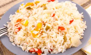 Une assiette de riz créole coloré avec des morceaux de poivrons rouges et jaunes.