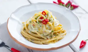 Un plat de spaghetti carrettiera crémeux, garni de piments rouges frais et de persil, prêt à être dégusté.