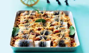 Sardes à beccafico, un plat sicilien appétissant, garni de chapelure, pignons et raisins secs, dans un plat de cuisson.