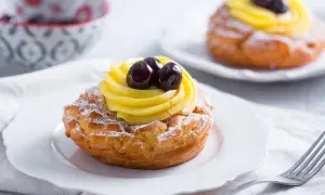 Zeppole di San Giuseppe, des pâtisseries italiennes garnies de crème pâtissière et de cerises, saupoudrées de sucre glace.