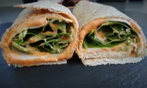 Deux moitiés d'un wrap jambon garni de feuilles de laitue croquantes et d'une sauce crémeuse.