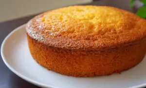 Un délicieux gâteau mandarine, doré et moelleux, posé sur une assiette blanche. Parfait pour le goûter.