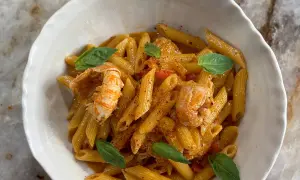Un plat de pâtes aux langoustines, garni de feuilles de basilic frais et d'une sauce onctueuse. Un délice pour les amateurs de fruits de mer.