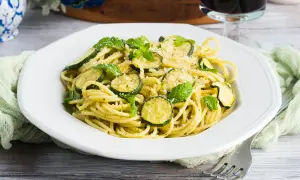 Spaghetti alla Nerano, un plat de pâtes crémeux aux courgettes et à la menthe fraîche, garni de parmesan râpé.