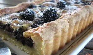 Tarte rectangulaire aux mûres, saupoudrée de sucre glace. Une délicieuse recette de tarte aux mûres, parfaite pour l'été.