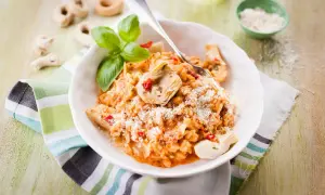 Un délicieux risotto pesto rosso, garni d'artichauts et de basilic frais, saupoudré de parmesan.