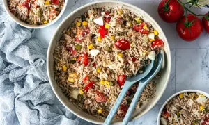 Une généreuse salade de riz italienne, garnie de thon, tomates, maïs et œufs durs, prête à être dégustée.