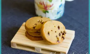 Pile de biscuits au café parsemés de pépites de chocolat, sur une petite palette en bois.