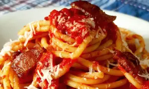 Un plat de pâtes amatriciana, avec des morceaux de guanciale croustillant, une sauce tomate riche et du fromage râpé.