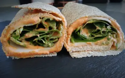 Deux moitiés d'un wrap jambon garni de feuilles de laitue croquantes et d'une sauce crémeuse.