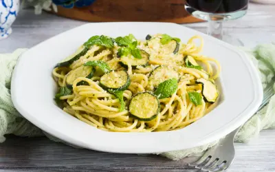 Spaghetti alla Nerano, un plat de pâtes crémeux aux courgettes et à la menthe fraîche, garni de parmesan râpé.