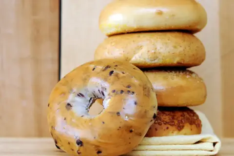 Pile de bagels, dont un aux myrtilles en premier plan. Parfait pour une recette bagel maison.
