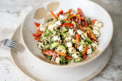 Salade quinoa colorée avec des dés de feta, concombre, poivrons rouges et herbes fraîches. Un plat sain et savoureux.