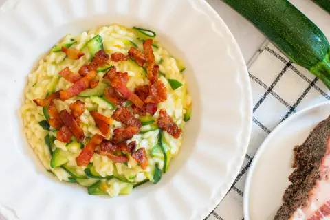 Risotto crémeux aux courgettes, garni de croustillantes tranches de guanciale. Un délice italien.