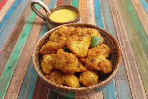 Beignets de choux-fleur italiens dorés et croustillants, servis dans un bol avec une sauce crémeuse.