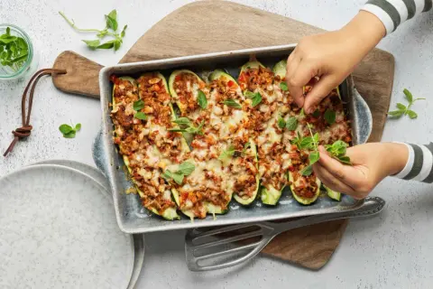 Courgettes farcies à la viande hachée, gratinées au fromage et garnies d'herbes fraîches. Une recette savoureuse prête à être dégustée.