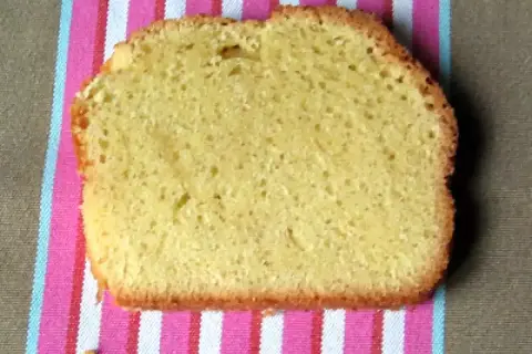 Une tranche de torta margherita, moelleuse et dorée, posée sur une serviette rayée rose et blanche.