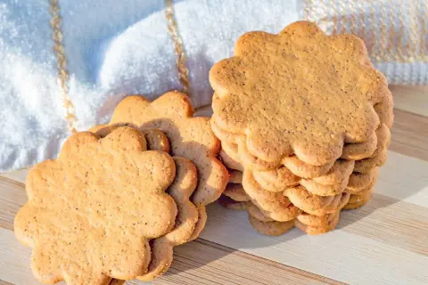 Délicieux biscuit sans beurre avec huile, en forme de fleur, empilés sur une planche en bois.