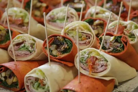 Plateau de wraps colorés, parfaits pour une recette facile et rapide. Garnitures variées visibles : légumes, charcuterie, sauce.