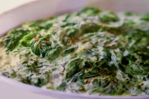 Un plat réconfortant d'épinards à la crème, parsemé d'épices, prêt à être dégusté.