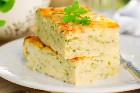 Deux parts de flan de courgettes facile, garnies de persil frais, sur une assiette blanche.
