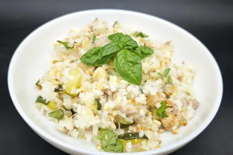 Un plat de riz aux courgettes et thon, garni de basilic frais. Une recette simple et savoureuse.
