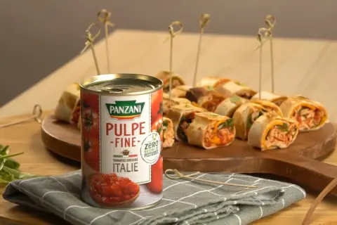 Délicieux wrap poulet garni de pulpe de tomate Panzani, présenté sur un plateau en bois avec des brochettes.