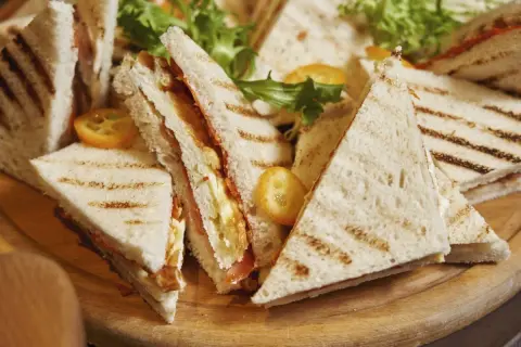 Tramezzini recette : des sandwichs triangulaires grillés, garnis de légumes frais et de garnitures savoureuses, prêts à être dégustés.