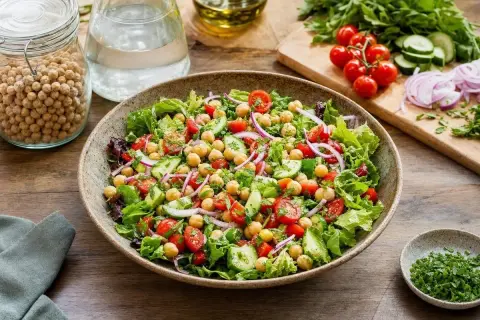 Salade composée fraîche et colorée avec pois chiches, tomates cerises, concombre et oignons rouges. Un délice sain et léger.