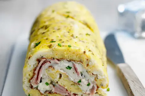Une savoureuse omelette roulée au four, garnie de jambon et de fromage frais, parsemée de ciboulette. Un délice !